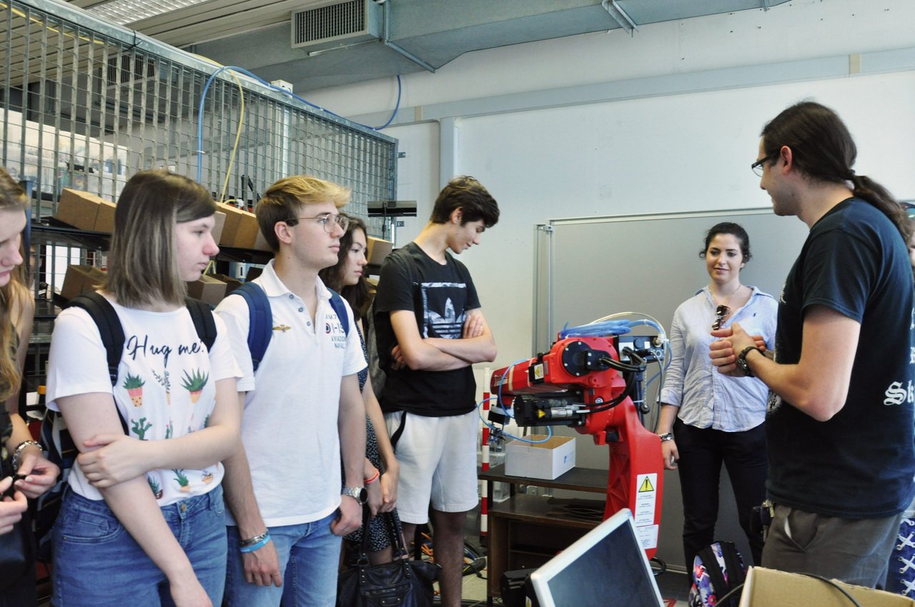Foto della dell'edizione 2025 di techcamp: un professore spiega ad un gruppo di ragazzi il funzionamento di una macchinario