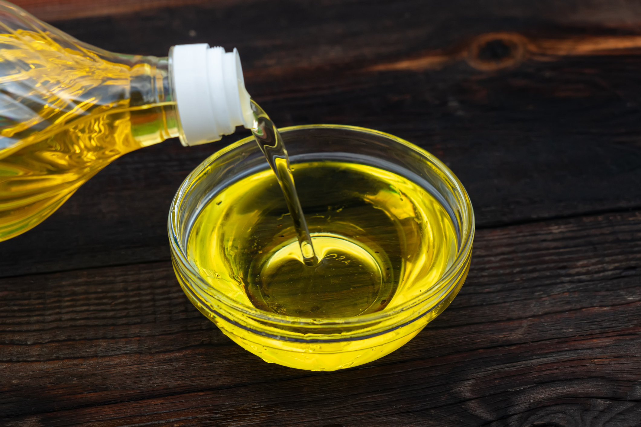 Oil poured from a bottle into a glass bowl